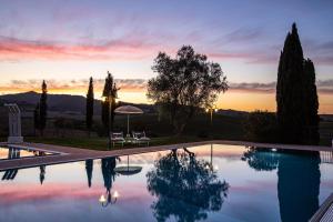 uma piscina com um pôr-do-sol ao fundo em Appartamento in casale con piscina Casa I Pavoni em Chianni