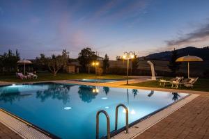 uma piscina à noite com cadeiras e guarda-sóis em Appartamento in casale con piscina Casa I Pavoni em Chianni