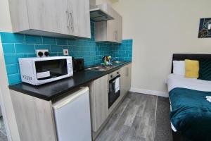 a small kitchen with a microwave and a bed at Cosy Studio 3 mins Walk To Coventry Cathedral in Coventry