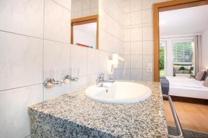 ein Badezimmer mit Waschbecken und ein Zimmer mit Bett in der Unterkunft Zillertal Appartements in Fügen + 37 Fotos