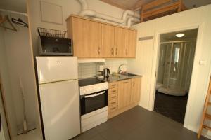 a kitchen with wooden cabinets and a white refrigerator at Arctic Seasport in Løding