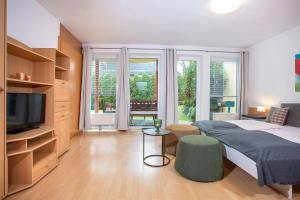 ein Schlafzimmer mit einem Bett und einem TV sowie einige Fenster in der Unterkunft Zillertal Appartements in Fügen