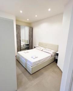 een witte slaapkamer met een groot bed en een spiegel bij La Dimora della Fenice in Fondi