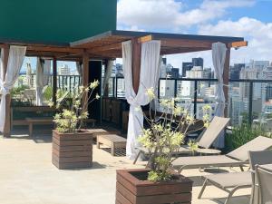 un patio en la azotea con cenador y cortinas blancas en Roof Top Bela Cintra Residence, en São Paulo