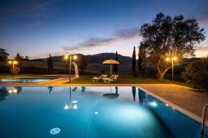 基昂尼的住宿－Appartamento in casale con piscina Casa I Pavoni，一个带桌子和遮阳伞的游泳池