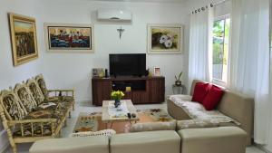uma sala de estar com um sofá e cadeiras e uma televisão em Linda Casa de Praia (Morada 3R's) Florianópolis/SC em Florianópolis