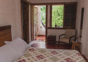 1 dormitorio con cama, ventana y silla en Fazenda Dos Cordeiros, en Imbau