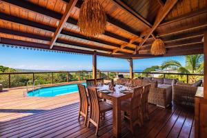 a wooden deck with a table and chairs and a pool at KAZ PASSION - Villa Haut de gamme in Rivière
