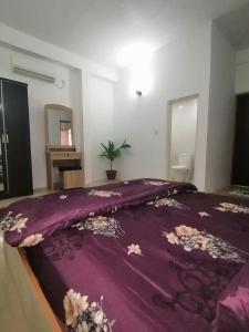 - une chambre avec une couverture violette sur un lit dans l'établissement The Rose Garden House, Addu City, Maldives, à Hithadhoo