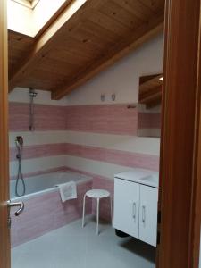 a bathroom with a tub and a stool in it at Villetta Muncion in Pozza di Fassa