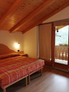 a bedroom with a bed and a large window at Villetta Muncion in Pozza di Fassa