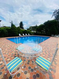 a glass table and two chairs and a swimming pool at Hotel Casa Blanca Campestre in La Mata