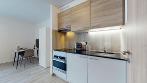 uma cozinha com armários brancos, um lavatório e uma mesa em Nonanteneuf appart hōtel Aigle - contactless check-in em Aigle