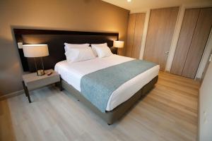 1 dormitorio con 1 cama grande y mesita de noche con 2 lámparas en Estelar Apartamentos Medellin en Medellín