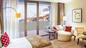 ein Hotelzimmer mit einem Bett, einer Couch und einem Fenster in der Unterkunft AlpenGold Hotel Davos in Davos