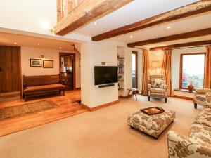 Una sala de estar con un sofá y un televisor. en Bent Chapel Cottage, en Matlock