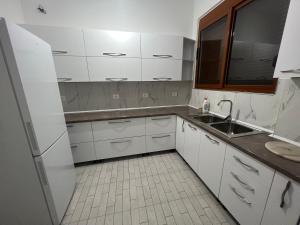 Una cocina con gabinetes blancos y un fregadero. en Vlore , Lungomare, en Vlorë