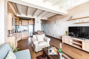 ein Wohnzimmer mit Couch und Fernseher und eine Küche in der Unterkunft Warda C11 Apartment by Wonderful Italy in Desenzano del Garda