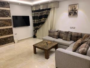 a living room with two couches and a flat screen tv at Le Royal Residence 1 in Cairo