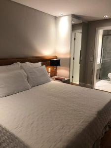 um quarto com uma grande cama branca e uma janela em PRAIA BRAVA HOTEL em Florianópolis