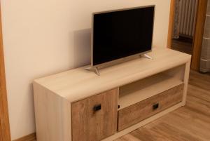 TV de pantalla plana en la parte superior de un soporte de madera en Apartman Kovač, en Pale