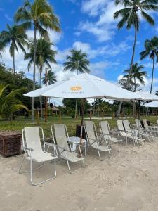 a row of chairs and an umbrella on the beach at Flat 208 Eco Resort Carneiros in Tamandaré