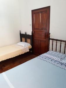 two beds in a room with a door at Casa do Peregrino - Confortável no centro in Paraisópolis