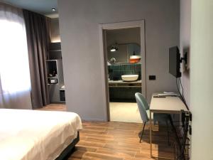 sypialnia z łóżkiem i biurkiem oraz łazienka w obiekcie Materiaprima camere-rooms w mieście Mantova