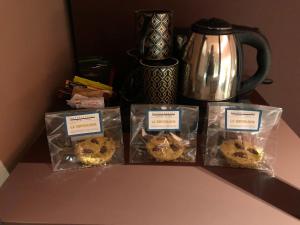 tre muffin in sacchetti di plastica su un bancone con bollitore per il tè di Materiaprima camere-rooms a Mantova