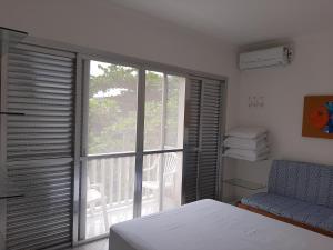 - une chambre dotée d'une fenêtre avec un lit et une chaise dans l'établissement Apto 1 dorm Guarujá, Enseada, 1 quadra da praia, à Guarujá