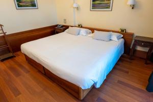 a large white bed in a room with wooden floors at Golf Hotel La Pinetina in Appiano Gentile