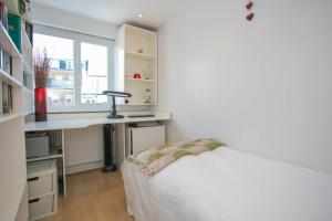 um quarto com uma cama, uma secretária e uma janela em Stunning 3 Bedroom House with Garden in Battersea em Londres