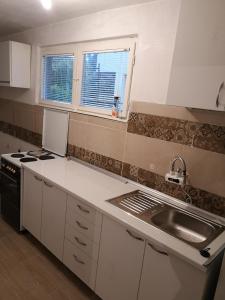 uma cozinha com armários brancos, um lavatório e uma janela em White Night em Skopje