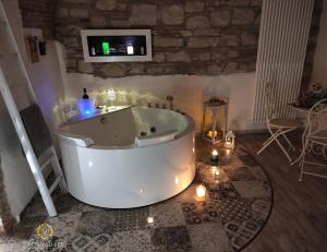 VenuSuite VENOSA - Luxury House, Spa & Relax - في فينوسا: حوض استحمام في غرفة مع الشموع وتلفزيون