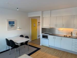 cocina con armarios blancos, mesa y sillas en Nuuk Hotel Apartments by HHE en Nuuk
