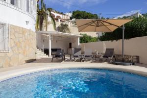 a swimming pool with an umbrella next to a house at Casa Altavista in Benissa
