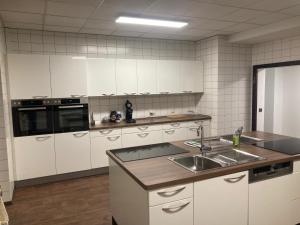 una cucina con armadi bianchi e lavandino di Apartmenthaus a Lingen