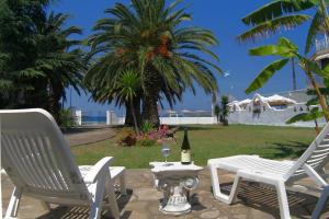 two white chairs and a table with a bottle of wine at Villa Paradiso in Neos Marmaras