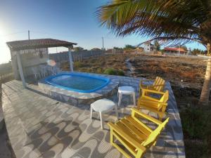 a patio with chairs and a swimming pool and a table at Pires House Beach Maramar in Luis Correia