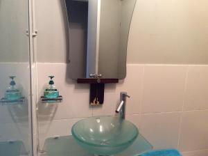 baño con lavabo verde y espejo en Neptune Coastal Haven, en Auckland