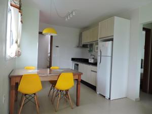 a kitchen with a wooden table and yellow chairs at Beira Mar Village in Pinheiro