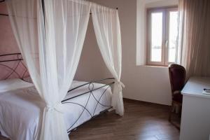 a bedroom with a bed with white curtains and a window at Fattoria L'Olmetto in Pisa