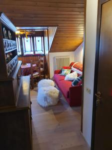 ein Wohnzimmer mit einem roten Sofa und einem Tisch in der Unterkunft DELIZIOSA MANSARDA in Madonna di Campiglio