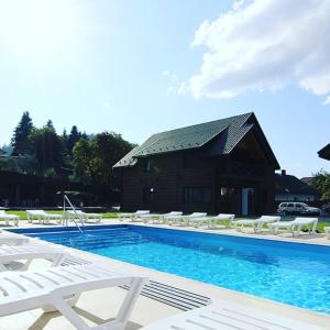 a swimming pool with lounge chairs and a building at Villa Paraiso Karpaty in Tesnyts'ka