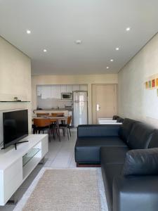 a living room with a blue couch and a kitchen at Apartamento em Resort Ilha da Madeira na Riviera in Riviera de São Lourenço