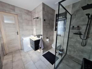 La salle de bains est pourvue d'une douche, d'un lavabo et de toilettes. dans l'établissement Słoneczny Zakątek, à Lubrza