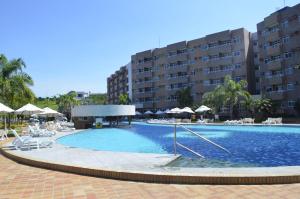 a large swimming pool with chairs and umbrellas next to a building at Quarto em Gran Lençóis Flat Residence in Barreirinhas
