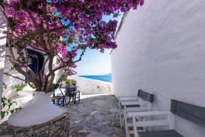Habitación con paredes blancas y un árbol con flores púrpuras. en Villea Seaview Apartments en Skopelos Town