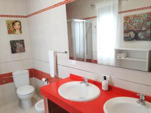 łazienka z 2 umywalkami, toaletą i lustrem w obiekcie LA CASA DE LA PINTORA DE CAZORLA,ideal para familias y grupos grandes w mieście Cazorla +10 zdjęć