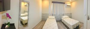 um quarto com duas camas e um espelho em Hotel Avalon Maringá Econômico em Maringá